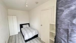 a small bedroom with a bed and white walls at Aaby House in London in Croydon