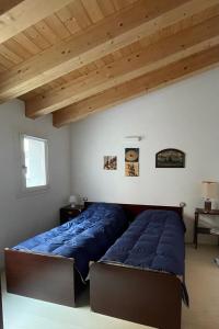 Un dormitorio con una cama con sábanas azules y techos de madera. en PORTOPICCOLO sul Mare Sistiana, en Sistiana