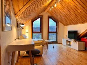 a living room with windows and a desk and a television at Eifel-Ferienhaus Lavendel in Simmerath
