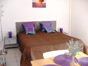 レ・ザドレ・ド・レステレルにあるSoleil Rougeのベッドルーム1室(紫と青の枕が備わるベッド1台付)