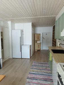 una cucina con elettrodomestici bianchi e soffitto in legno di Granny´s House Kuusela a Portimo