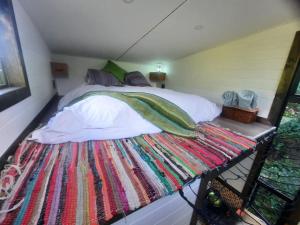 a bed in a small room with a colorful rug at Tiny Home Trails End in Lovemore Park