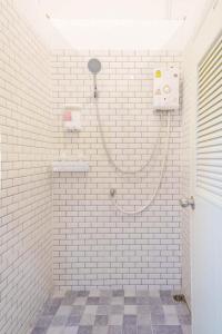 a white tiled bathroom with a shower with a hose at Lamoon Hostel in Hat Yai