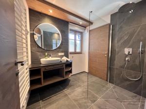 ein Bad mit einem Waschbecken, einer Dusche und einem Spiegel in der Unterkunft Adlhof Apartments in Bruneck