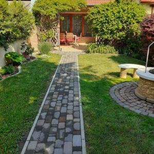 a garden with a brick path in front of a house at Lux Apartman Villa in Hajdúszoboszló