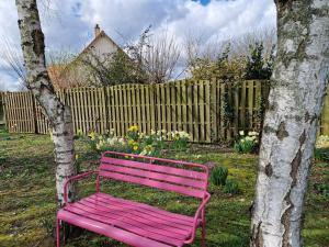 un banc rose assis à côté d'un arbre et d'une clôture dans l'établissement Leira, 