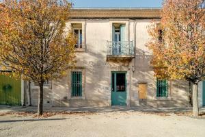 um edifício com uma porta verde e duas árvores em appartement 30m2 calme proche du centre ville em Lunel