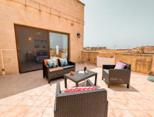 eine Terrasse mit Sofas, einem Tisch und Stühlen in der Unterkunft Villa Fieldend - Gozo Holiday Home in Għarb