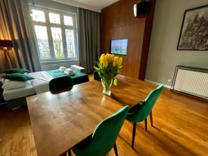 comedor con mesa de madera y sillas verdes en Lou Lou Apart Wawel, en Cracovia