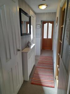 a hallway with a door and a mirror and a rug at Charming Eyemouth apartment close the beach in Eyemouth