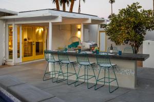 a patio with a bar with four chairs around it at For The Record in Palm Springs