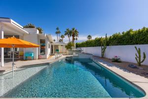 een zwembad met een parasol naast een huis bij For The Record in Palm Springs