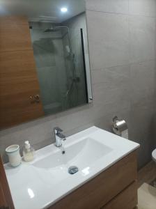 ein Badezimmer mit einem weißen Waschbecken und einem Spiegel in der Unterkunft Piso 1ª Línea Y Céntrico in Peñíscola