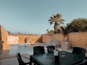 um pátio com uma mesa e cadeiras ao lado de uma piscina em Villa Fieldview - Gozo Holiday Home em Gharb