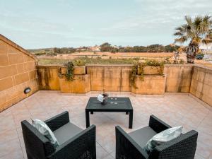 a patio with two chairs and a table at Villa Fieldview - Gozo Holiday Home in Għarb