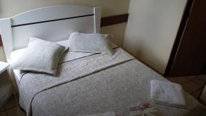 1 dormitorio con 1 cama con sábanas y almohadas blancas en Escuna Praia Hotel, en João Pessoa