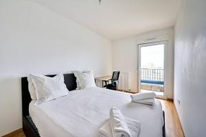 a white bedroom with a large bed with a window at Magnifique F3 à moins de 15 min de la défense in Nanterre