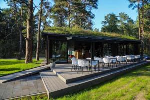 a building with a grass roof with a table and chairs at Seaside apartment Albatross, spa and pool in Ķesterciems