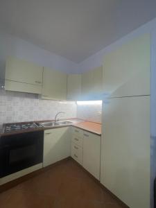 een keuken met witte kasten, een wastafel en een fornuis bij Design apartments - B in Siniscola