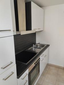 een kleine keuken met witte kasten en een wastafel bij Ferienwohnung Elbtraum in Pirna