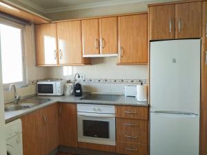 Una cocina con gabinetes de madera y un refrigerador blanco. en Apartamento Don Gustavo Attic, en Benalmádena 2 fotos más