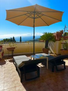 einen großen gelben Regenschirm auf einer Terrasse mit einem Tisch und einer Bank in der Unterkunft Villa Greta Hotel Rooms & Suites in Taormina
