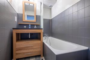łazienka z wanną, umywalką i lustrem w obiekcie Superbe appartement avec parking gratuit en centre ville et aux pieds des pistes w Chamonix-Mont-Blanc