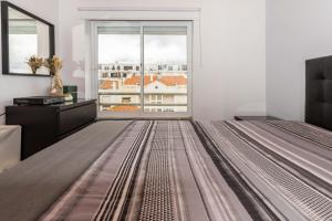 ein Schlafzimmer mit einem Bett und einem großen Fenster in der Unterkunft THE ATTIC - Caparica Beach and Surf Apartment in Costa da Caparica