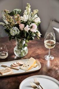 een tafel met een vaas met bloemen en een bord kaas bij Chaplet Cottage Luxury Healesville Cottage in Healesville