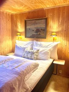 a bedroom with a bed with white sheets and two lamps at Rostad Retro Rorbuer in Reine