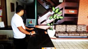 un hombre parado en un mostrador con un portátil en Escuna Praia Hotel, en João Pessoa