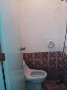 a bathroom with a white toilet and a tile wall at NatureswayBudget room Travel in Coron
