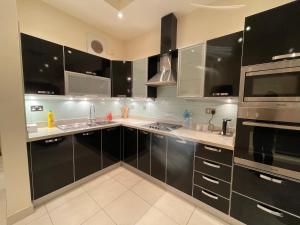 uma cozinha com armários pretos e electrodomésticos de aço inoxidável em Premium 2 Bedroom Flat em Manama