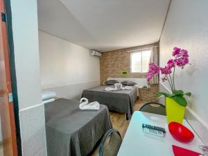 a room with two beds and a table with a vase of flowers at Hotel Cajuína Beach in Parnaíba