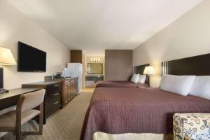 Habitación de hotel con 2 camas, escritorio y TV. en Travelodge by Wyndham Kamloops Mountview, en Kamloops