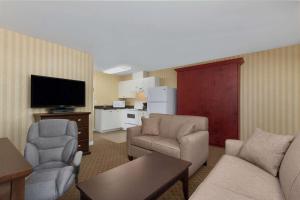a living room with a couch and chairs and a tv at Travelodge by Wyndham Kamloops Mountview in Kamloops