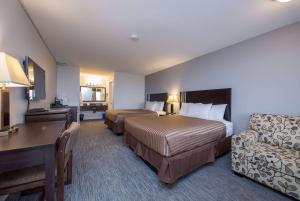 um quarto de hotel com duas camas, uma secretária e uma cadeira em Travelodge by Wyndham Kamloops Mountview em Kamloops