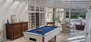 a room with a pool table in a room withwindows at La Bastide des Arts in Saumane-de-Vaucluse