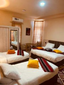a hotel room with three beds with yellow pillows at Petra fort hotel in Wadi Musa +85 photos