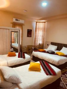 a hotel room with three beds with yellow pillows at Petra fort hotel in Wadi Musa
