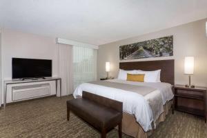 a hotel room with a bed and a flat screen tv at Wyndham Garden Fresno Yosemite Airport in Fresno