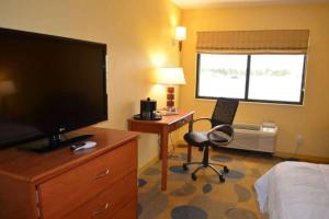 Habitación de hotel con TV y escritorio con silla. en Marble Waters Hotel & Suites, Trademark by Wyndham, en Jacksonville