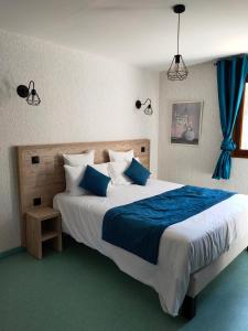 a bedroom with a large bed with blue and white pillows at Auberge Du Riou in Puget-Rostang