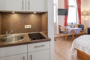eine Küche mit einem Waschbecken und ein Zimmer mit einem Bett in der Unterkunft Appartementhaus Alte Post in Langeoog