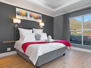 une chambre avec un grand lit sur lequel se trouvaient deux peluches dans l'établissement Villa de la Mer Hout Bay Beachfront, au Cap