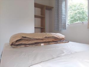 Una cama con una manta junto a una ventana en Camping de Retourtour, en Lamastre