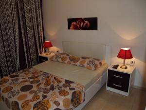 ein Schlafzimmer mit einem Bett und zwei Nachttischen mit Lampen in der Unterkunft Royal 2 in Avsallar