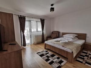 a bedroom with a bed and a chair and a window at Casa Dana Olteanu in Moieciu de Sus