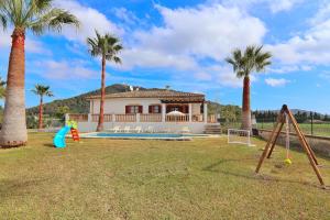uma casa com piscina e palmeiras e um parque infantil em Villa Can Mussol 040 by Mallorca Charme em Sa Pobla