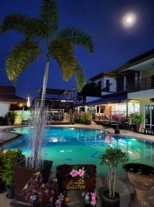 einen Swimmingpool mit Palme in der Nacht in der Unterkunft Baan Sabaijai Resort & Omsorgssenter in That Phanom